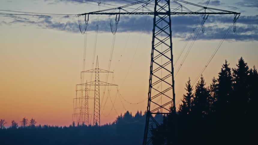 Towers with power lines against the sunrise sky
