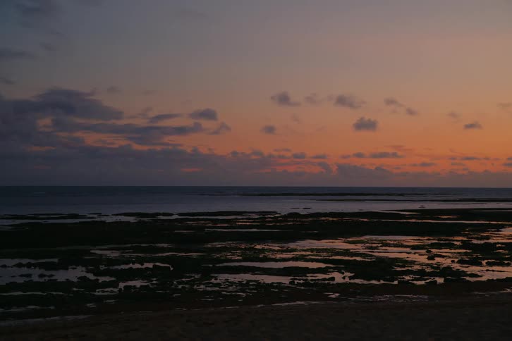 The sun is rising on the shore