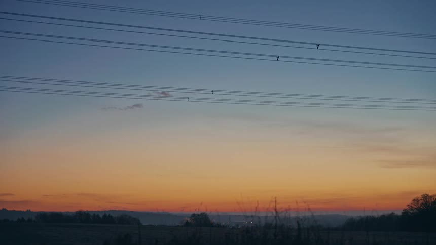 A landscape of a sky with orange lights in the horizon