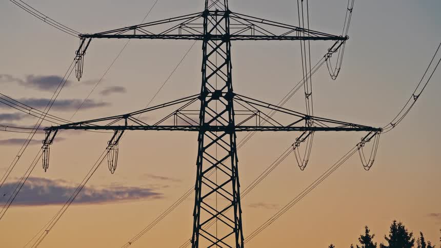 Power transmission tower with cables stretched against the evening sky