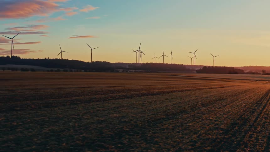 Turbines spin on a wind farm overlooking rural farmland