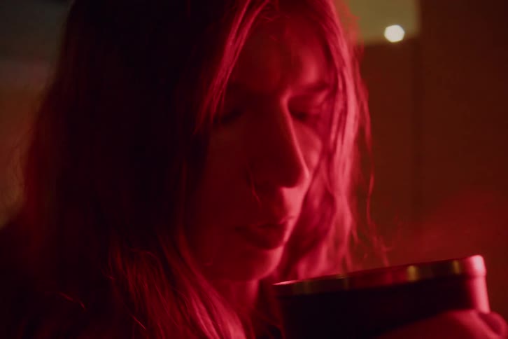 Closeup face of a woman drinking a hot beverage in a dark room at night