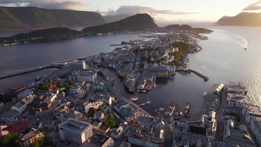 Aerial view reveals coastal town embraced by mountains and sea bathed in gentle morning light
