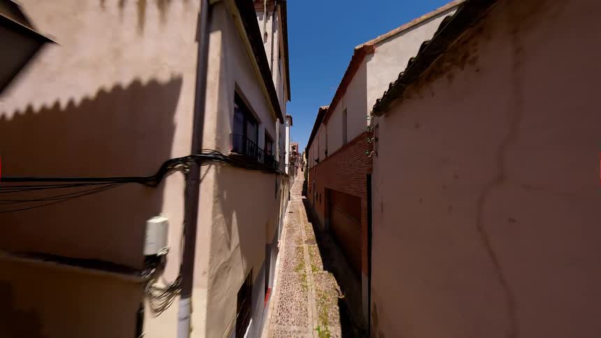 Narrow street between residential buildings with lightcolored facades under a blue sky