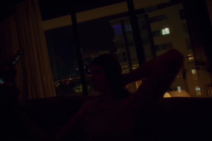 Woman sitting on sofa at night looking at her cell phone taking a selfie