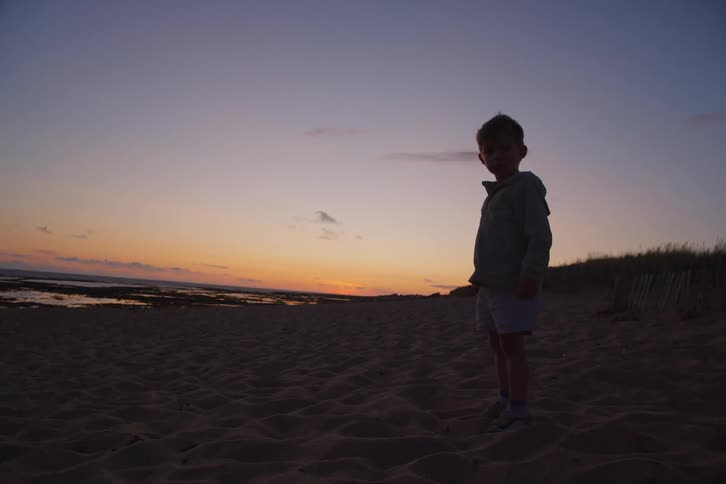 The boy plays in the sand at sunrise