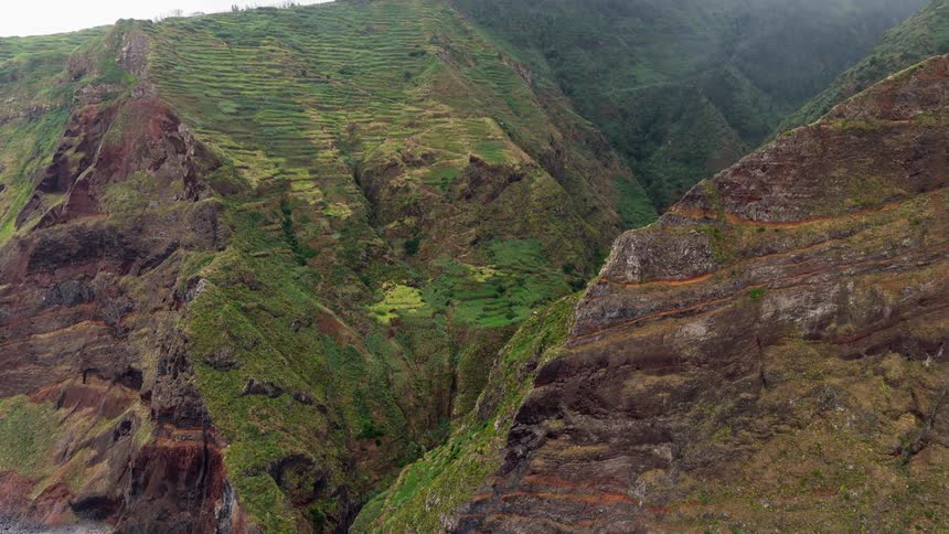 Mountain slopes with green terraces and rock formations seen from above