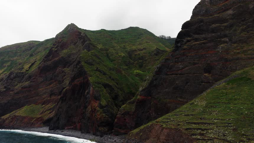 Mountains along the coast as waves roll in to shore