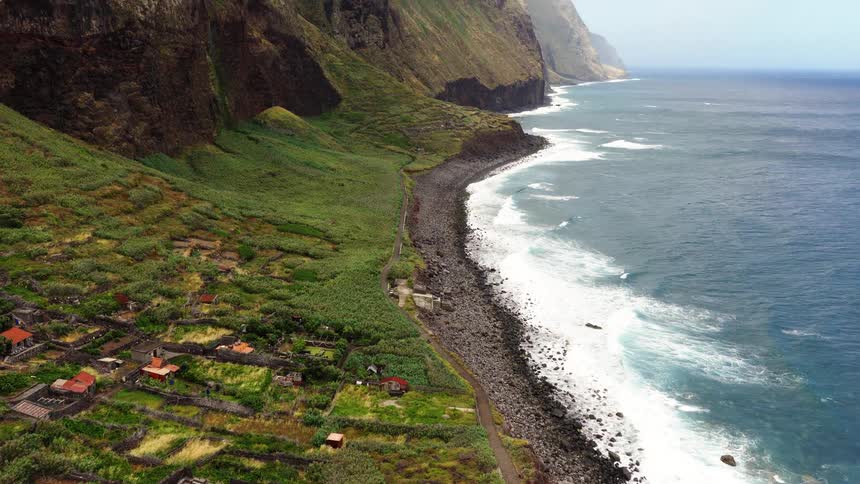 Coast line on an area next to the ocean with a cliff and a rural village outdoors during day time