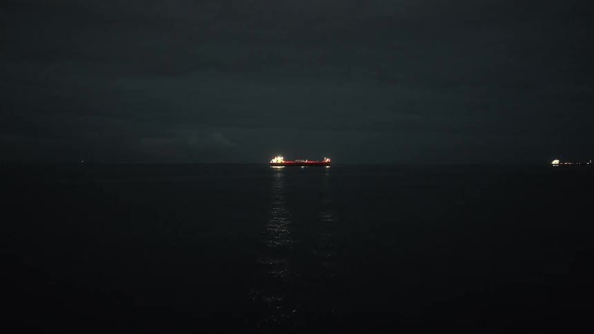 The boat is lit up in the distance