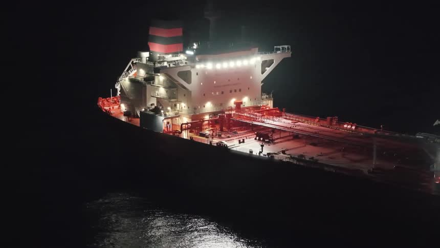 Illuminated oil tanker with reflections on water