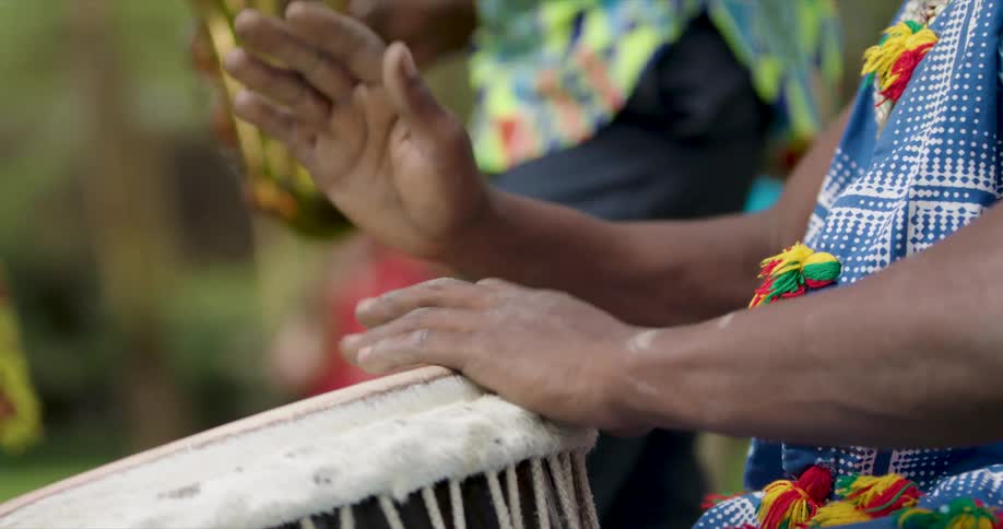 A man using a hand drum outdoors