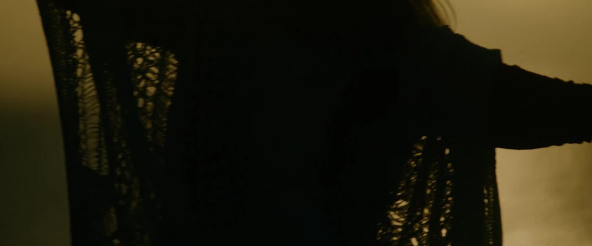 A woman is seen in silhouette against a golden sunset slowly raising her arms and dancing as she moves her hands gracefully toward the sky