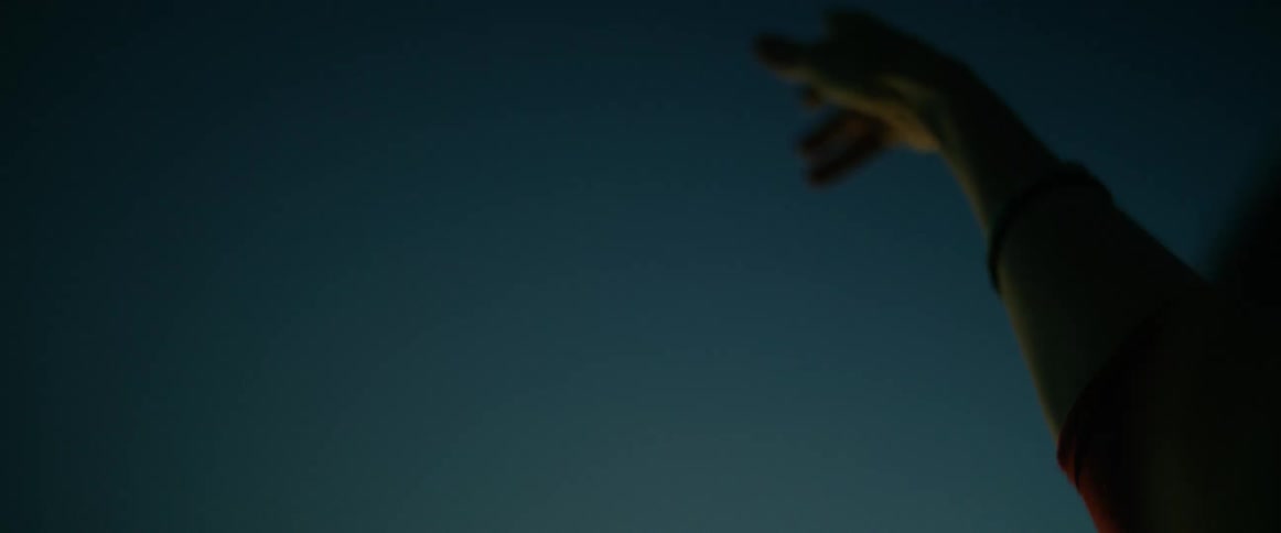 Female person making dance moves with her hands and arms outdoors during dusk or dawn