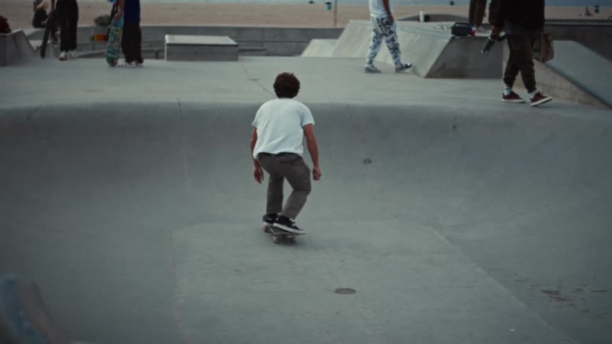 Skateboarder performs aerial trick above coastal bowl