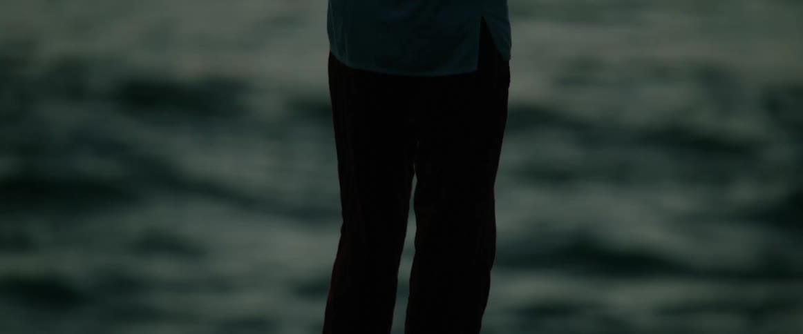Person plays flute by the water under soft light