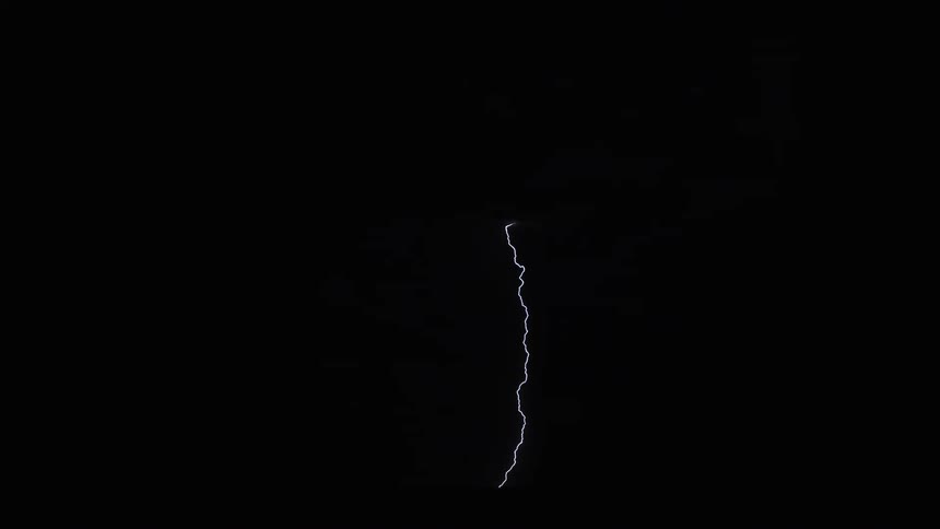 Lightning flashes and illuminates clouds as it strikes the ground