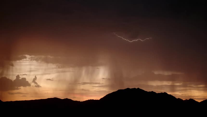 Thunderstorm dumps rain on the land as lightning strikes the mountain