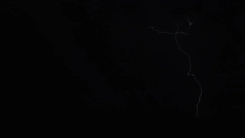 Lightning cracks across the sky and strikes the ground illuminating storm clouds in the darkness