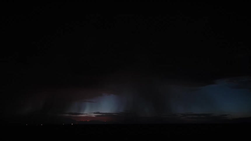 Powerful lightning flashes from dark clouds toward the horizon at deep blue twilight
