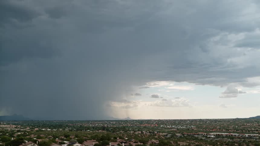 On a cloudy day in the city lightning strikes beneath the dark clouds at midday as a storm begins to form