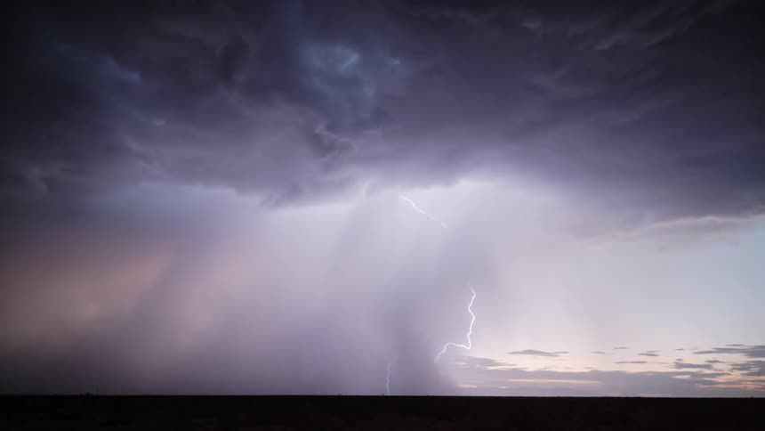 A storm forms over the ocean the sky covered in dark heavy clouds as lightning strikes beneath the swirling mass above the water