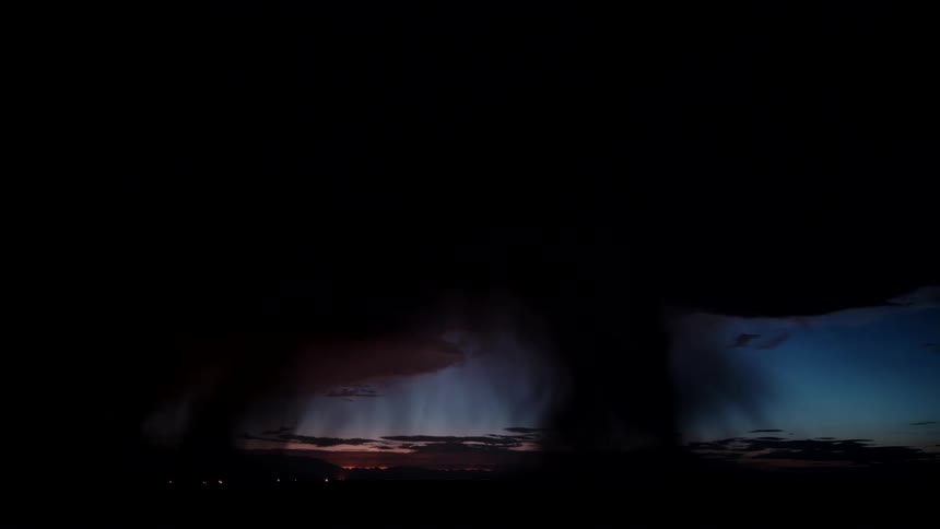 A wide view of a powerful lightning bolt striking the ground from heavy dark clouds during a storm at twilight with rain falling in the distance