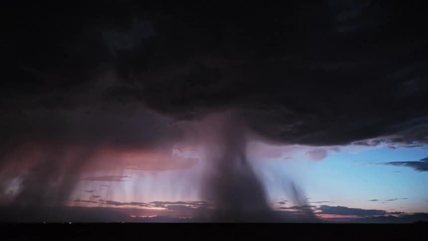 Thunder and lightning on heavy dark clouds over a flat area of land outdoors during dusk or dawn