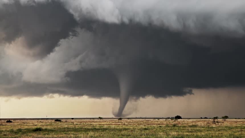 The tornado is moving across the field and you can see the clouds and funnel very clearly