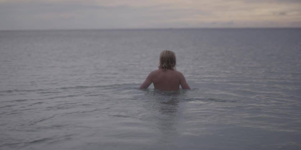 A man wades through chest deep ocean water