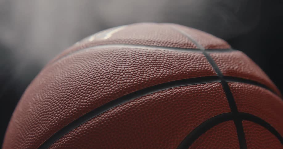 Basketball reveals pebbled texture against dark smoky background