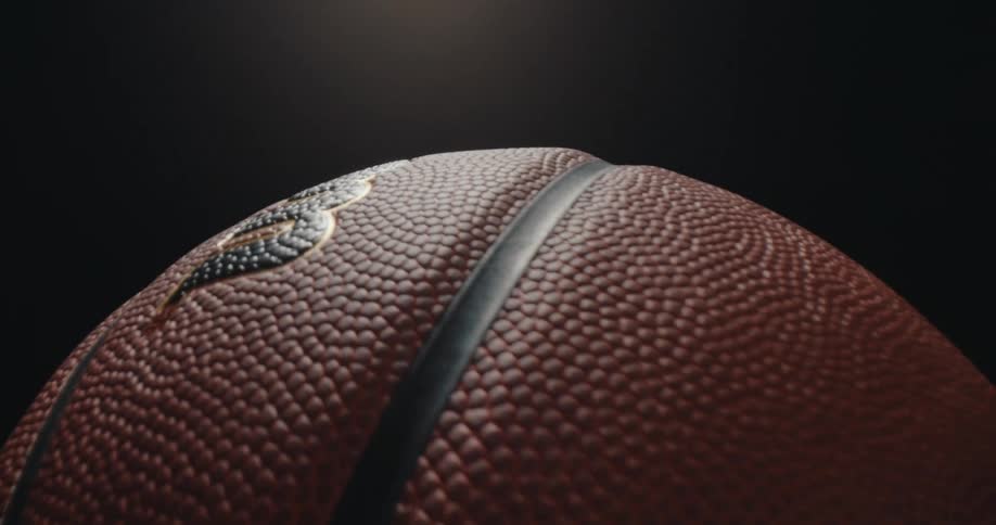 A wilson basketball slowly rotates against a dark studio background under a soft overhead light