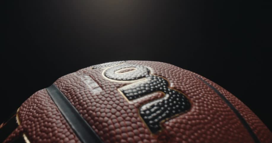 A closeup shot shows a wilson basketball slowly rotating against a dark background