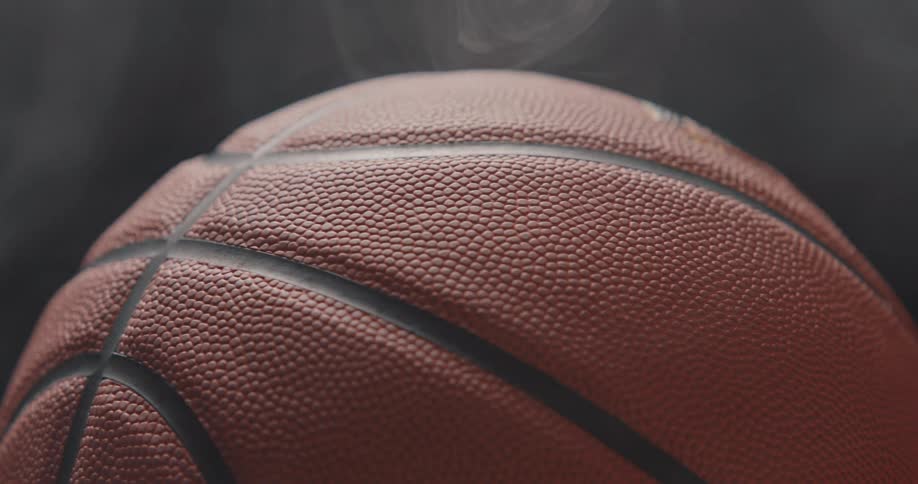 Pebbled texture and black grooves highlighted on basketball with misty background