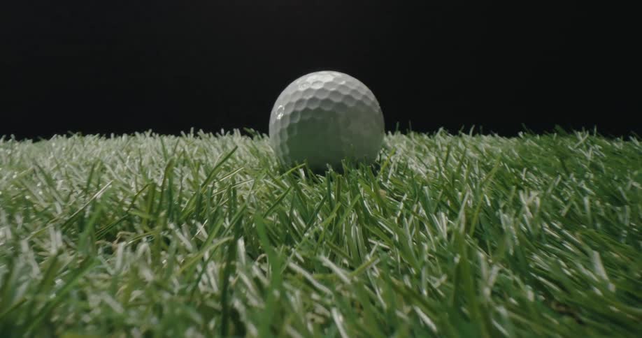 Golf ball rests on brightly lit grass