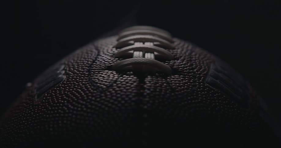 American football on a dark room surrounded by smoke indoors
