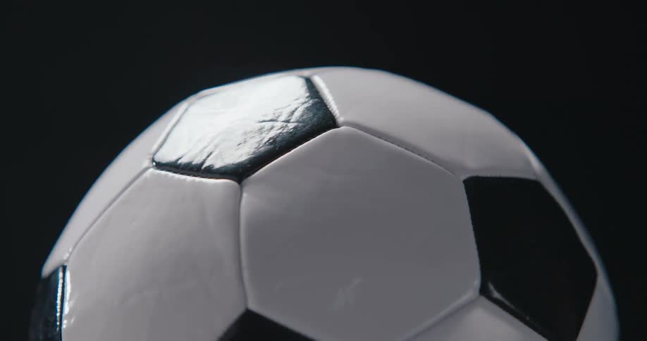 Light shines on a soccer ball as it turns and rotates