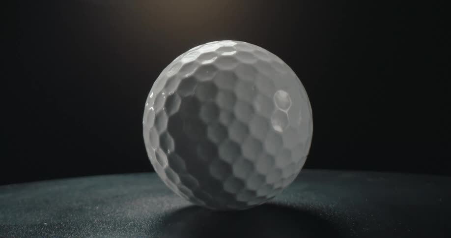 Light shines on a golf ball as it turns and rotates