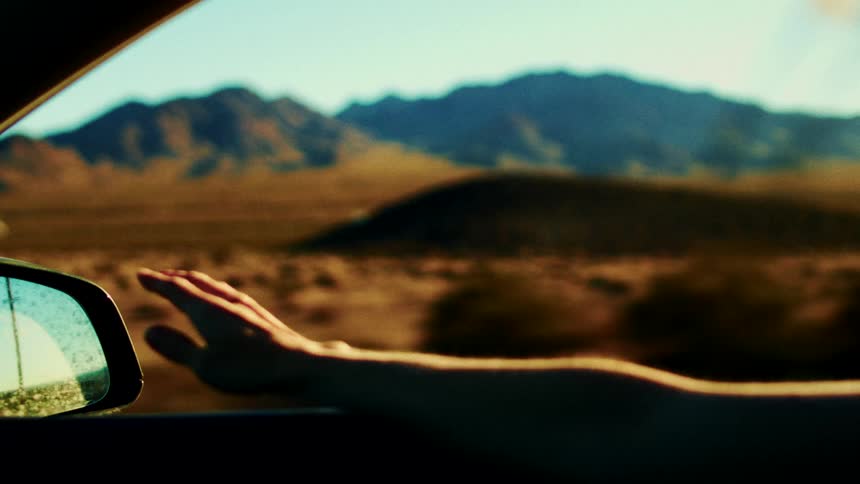 Person sitting on a car in movement with a natural landscape on the background outdoors during dusk or dawn