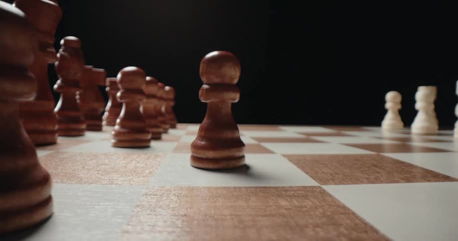 Human hand moving a wooden chess piece on a wooden chessboard indoors
