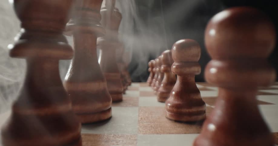 Smoke billowing between the chess pieces on a chessboard