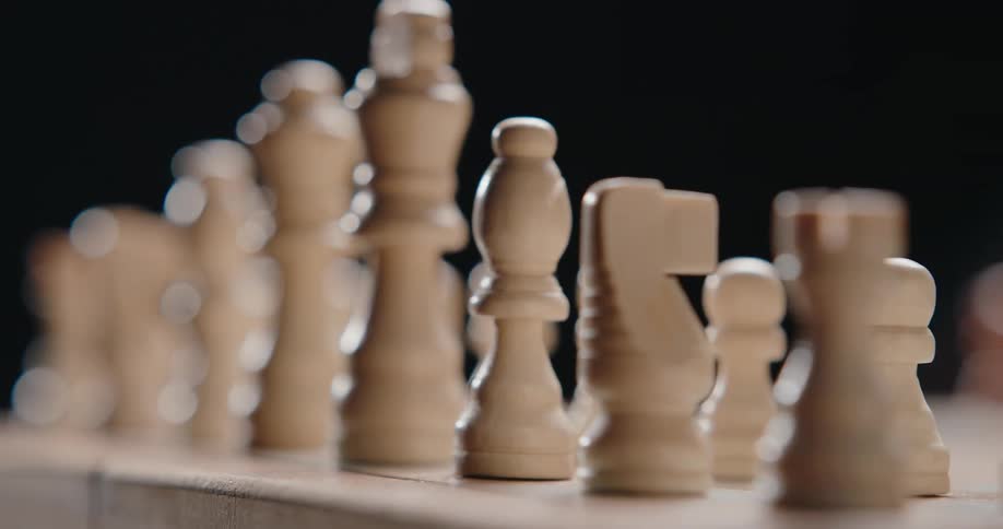 Wooden chess pieces arranged on a board with selective focus