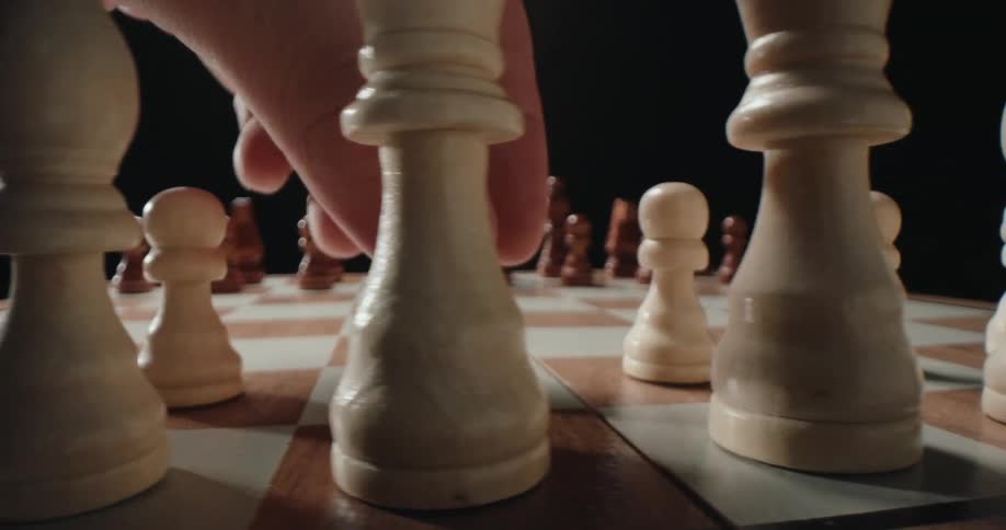 A person moves a piece on the chess board