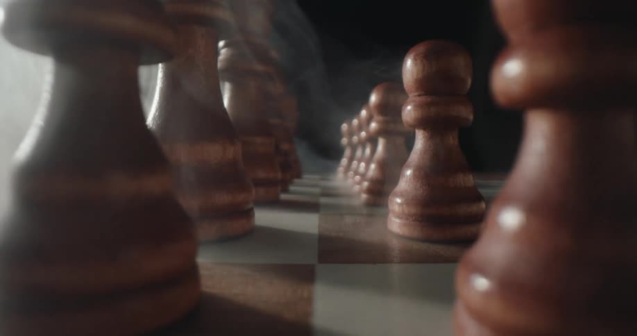 Closeup of wooden chess pieces arranged on a board with a dark moody backdrop