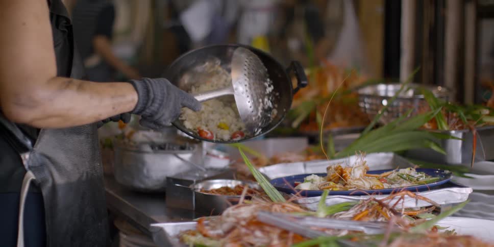 A man uses a large ladle to serve food from a pan