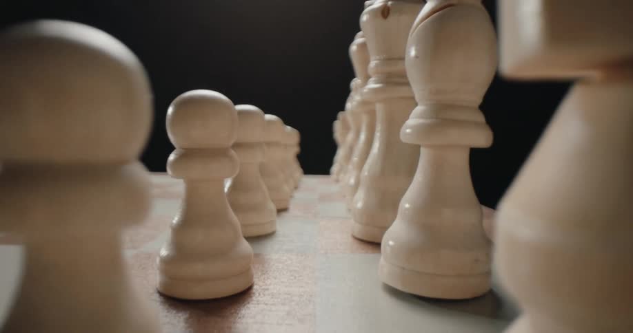 In the video provided the camera moves backward along a chess board to reveal two distinct lines of white chess pieces