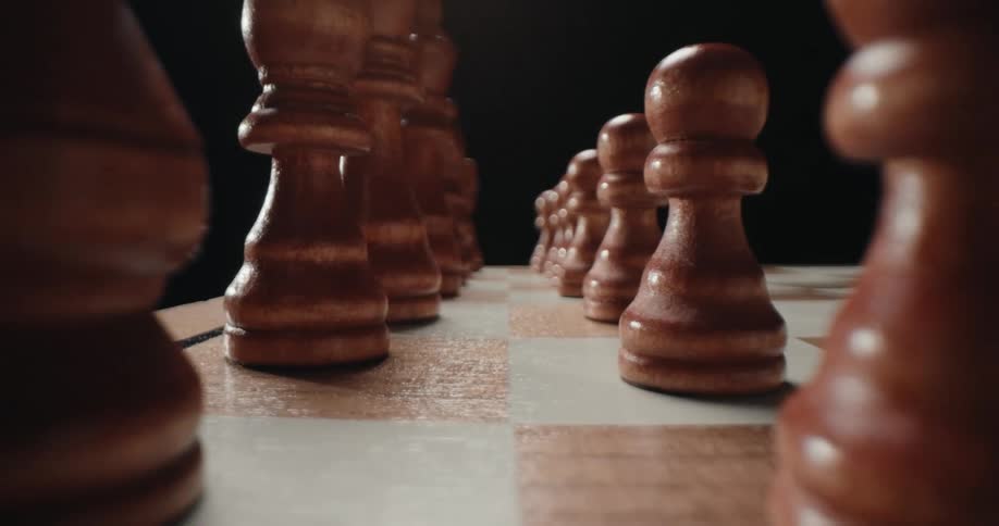 Wooden chess pieces aligned on a checkered board viewed from a lowangle perspective