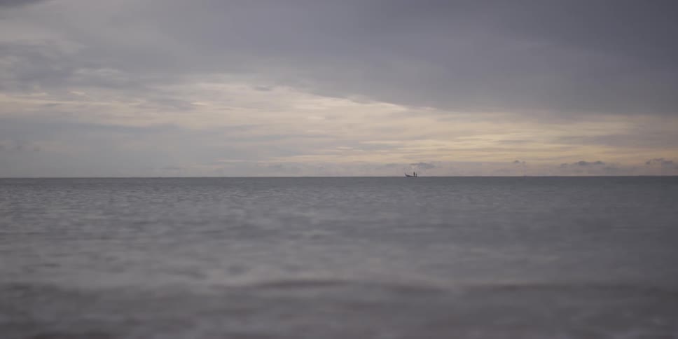A boat floating far away out in the middle of an ocean