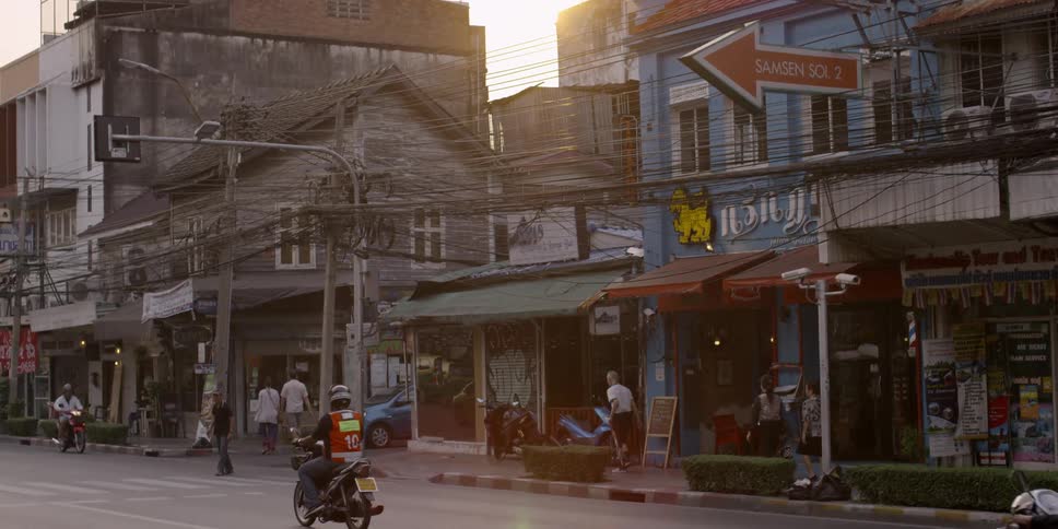 People walking and riding motorbikes in a busy city marketplace