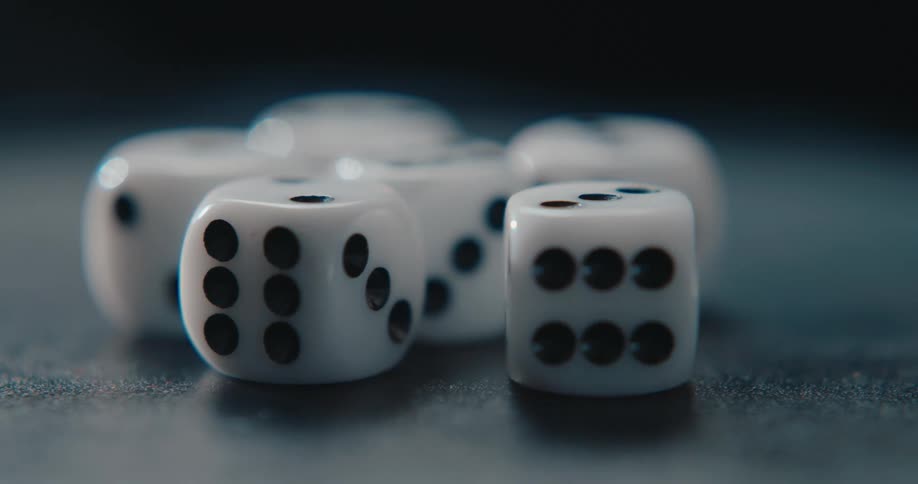 Six white dice with black pips across a dark textured surface in a closeup macro sho
